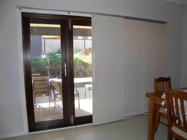 sliding panel blinds in blockout fabric over sliding door in half open position
